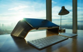 A clean desk with a laptop, keyboard and lamp.