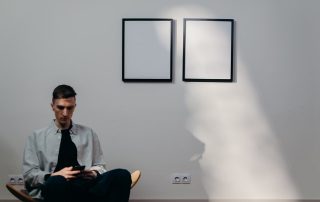 man sits in front of artwork looking at his phone